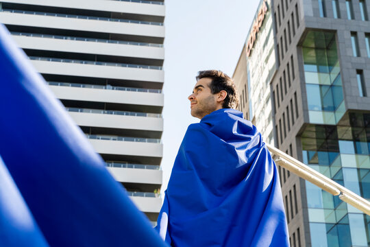 Businessman wearing superhero cape in the city