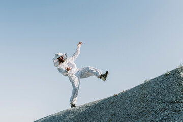 Man wearing a beekeeper dress tumbling on a hill