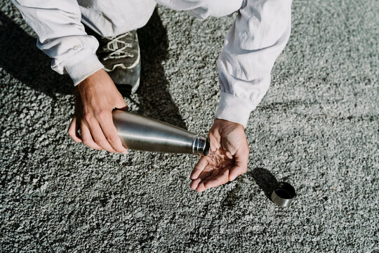 Man pouring water from thermos flask in an arid landscape