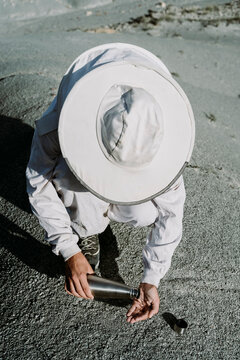 Man with thermos flask wearing a beekeeper dress in an arid landscape