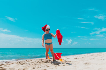 Naklejka na ściany i meble cute little girl celebrating christmas on tropical beach