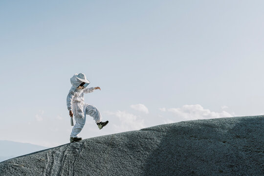 Man wearing a beekeeper dress stepping on a hill