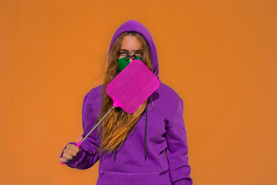 Teenage girl wearing protective face mask with fly sticker, holding swatter