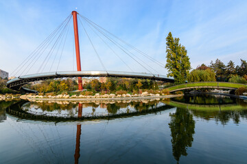 Fototapeta na wymiar Landscape with the lake and suspended bridge from Drumul Taberei Park, also known as Moghioros Park, in Bucharest, Romania, at sunrise in an autumn morning.