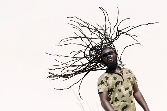 Rastafari man with sunglsasses tossing his dreadlocks