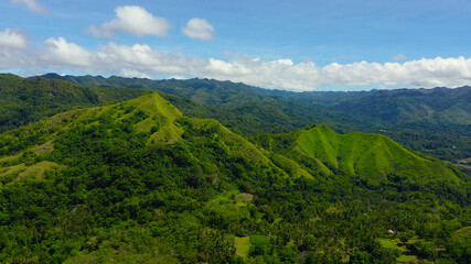 Tropical landscape: mountains with rainforest and hills with green grass.Mountains against the blue sky and clouds. Bohol, Philippines.