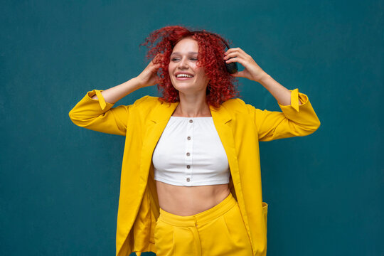 Young woman with red curly hair wearing headphones having fun listening music