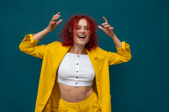 Young woman with red curly hair wearing headphones having fun listening music and dancing