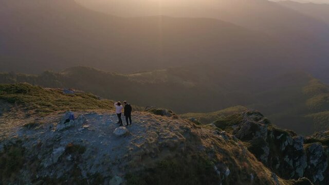 Tourists making pictures on high mountain top during sunset