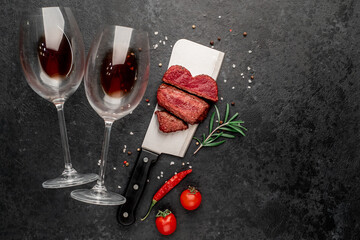 Dinner for two. Three pieces of meat. three types of grilled meats: rare, medium, well-done heart-shaped, bottle of wine and wine glasses on a stone background