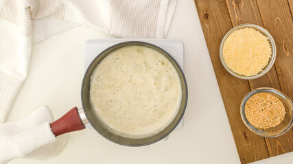 Alfredo sauce in saucepan, flat lay.  Asparagus casserole in a creamy Alfredo sauce topped with bread crumbs and Parmesan cheese step by step recipe.