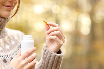 Woman hand holding a vitamin pill in autumn