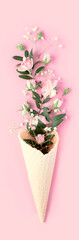 Fototapeta na wymiar Beautiful flowers in ice cream cone on pink background