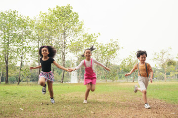 Obraz premium Group of kids running in the spring field at public park. Movement and blurry too soft. people children plying funny outdoors concept.