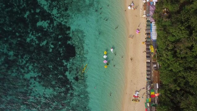 Aerial top down view of people enjoying summer at Puka Shell Beach on Boracay Island, Western Visayas, Philippines.