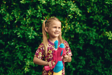 Portrait of a little white girl. Songkran Holiday in Hawaiian shirt  with plastic color water gun Thai holiday. Thai new year