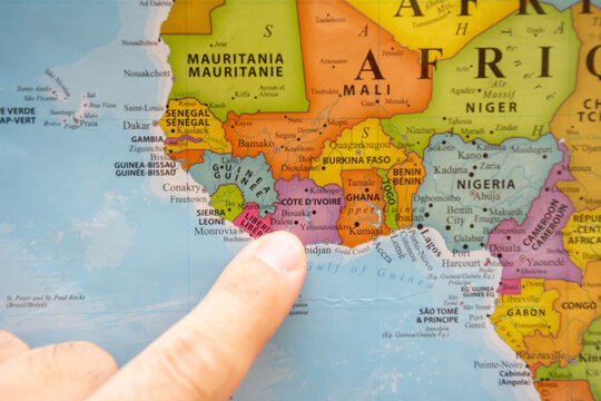 Finger pointing to a colorful country map in English and French Ivory Coast (Cote D'Ivoire)