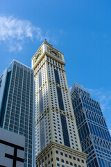 Fototapeta na wymiar Dubai International Financial Centre (DIFC) Iconic The Tower (clock) amid modern Dubai skyscrapers on blue sky.