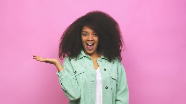 Young african american curly woman impressed holding copy space on palm