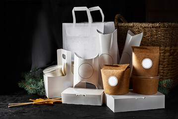 Eco craft paper tableware. Paper cups, dishes, bag, fast food containers, box for delivery food and wooden cutlery on a black background. Recycling concept.
