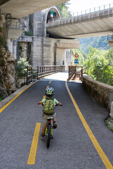 Ponteba Italy July 24th 2018. Ciclovia Alpe Adria with a little boy riding his bike on a former rail way. Radweg in Italian Alps.