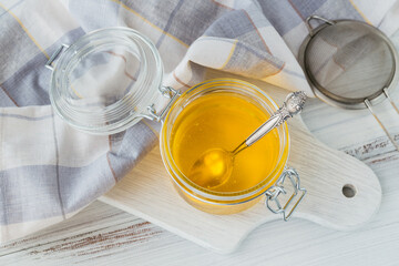 Healthy homemade Ghee or clarified butter in a jar on white wooden table. Healthy Ayurveda food concept.