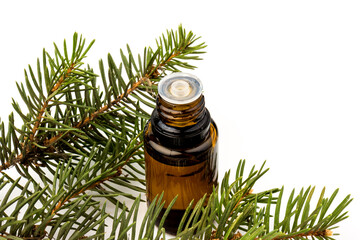Spruce essential oil in a bottle, with fresh spruce twigs on white background
