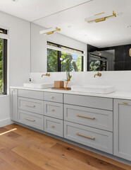 Bathroom in luxury home with double vanity, large mirror, sinks, cabinets, and hardwood floor