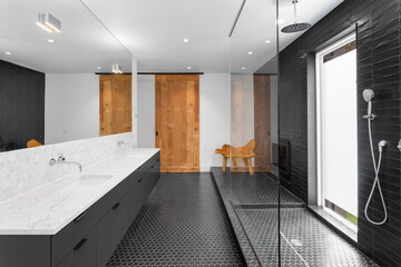 Bathroom in luxury home with walk-in shower, double vanity, mirror, sink, and tile floor.