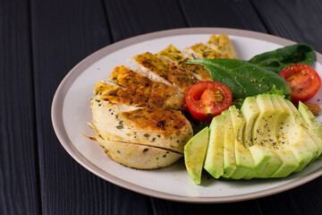 Healthy dietary salad with chicken fillet, avocado, nuts and fresh vegetables.Detox and healthy concept. Keto food. In a plate, on a wooden background.