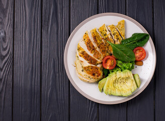 Healthy dietary salad with chicken fillet, avocado, nuts and fresh vegetables.Detox and healthy concept. Keto food. In a plate, on a wooden background.