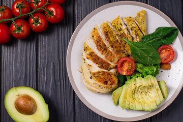 Healthy dietary salad with chicken fillet, avocado, nuts and fresh vegetables.Detox and healthy concept. Keto food. In a plate, on a wooden background.