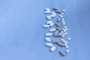 Assorted medical pills, tablets and capsules on blue background. Copy space