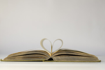 An old open book. I love reading. Close-up of book pages folded into a heart shape. Love of reading.