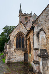 Fototapeta na wymiar Step back in time and visit Castle Combe, quaint village with well preserved masonry houses dated centuries back. St Andrew's Church with an old graveyard in picturesque medieval village in England.