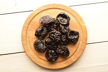 Sweet organic prunes on a plate, close-up, on a wooden table.