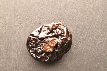Sweet organic prunes on a slate serving board, close-up, on a black background.