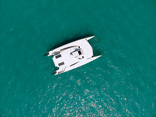 Picturesque top view of a huge white catamaran sailing across the deep sea. Aerial view.