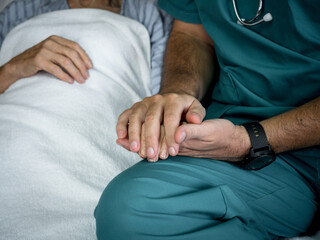 Doctor holding elderly woman patients hands in day hospital. Doctor helping elderly patients with Alzheimer's disease..