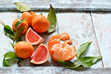 Ripe fresh tangerines with leaves on a wooden blue background. Fruit background, vegan food.
