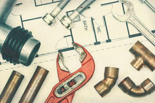 Vintage toned image of plumbing equipment and a blueprint project as a industrial background