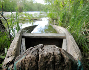 Old wooden broken boat for swimming on banks water in natural reeds
