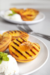 Delicious grilled peaches with ice cream and honey on grey table, closeup