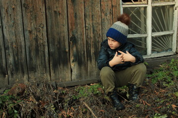 Fototapeta premium Lonely child is sitting next to the broken window