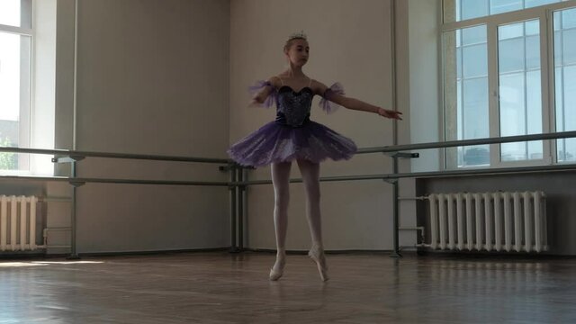 A teenage ballerina in a beautiful tutu trains and dances beautifully. Filmed in a dance studio.