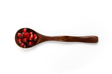 Top view. A wooden spoon with seeds in it. Wooden spoon with pomegranate seeds isolated on a white background. Fruit pomegranate. The concept of healthy eating.