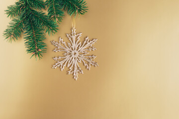 Golden snowflake with a spruce branches on a golden background. Christmas wallpaper or postcard concept.
