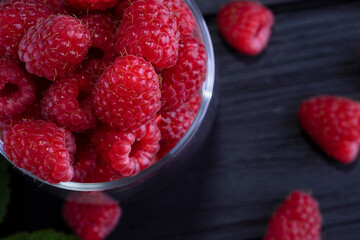 Raspberry. Fresh beautiful, red raspberries on a dark wood background. Green leaves. Place for text