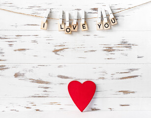 Valentines day red heart shape on white wooden background, inscription from wooden letters.