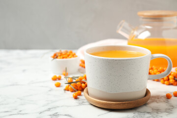 Delicious sea buckthorn tea and fresh berries on white marble table. Space for text